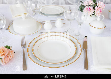 Table joliment décorée avec des assiettes, verres, couverts et des fleurs sur les nappes de luxe Banque D'Images