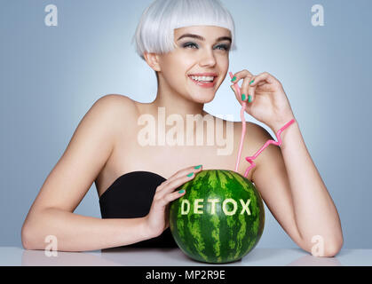 Funny smiling girl with watermelon cocktail. Photo de fashion fille blonde sur fond bleu. Concept Detox Banque D'Images