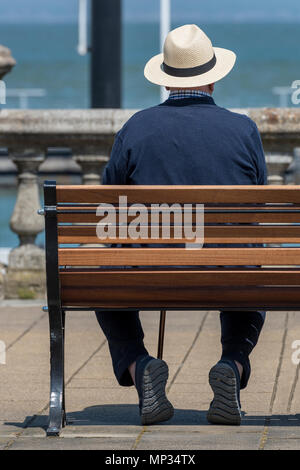 Un homme âgé portant un chapeau panama ou l'été à l'ombre de sa tête itting sur un banc au bord de la mer près de la côte en été. Casquettes chapeaux. Banque D'Images