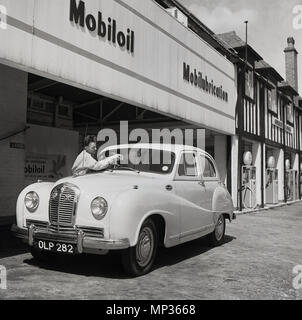 Années 1950, historique, un préposé de station service nettoyage du pare-brise avant d'une automobile, Londres, Angleterre, Royaume-Uni. Banque D'Images