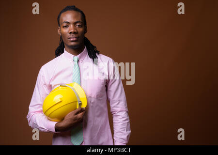 Beau jeune homme d'Afrique avec un casque de protection contre brown ba Banque D'Images