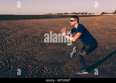 Jeune homme sur un pied de la pratique du yoga dans le sable de la plage de Sanlucar de Barrameda Banque D'Images