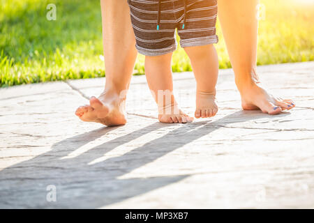 Mère et Bébé pieds prend des mesures à l'extérieur. Banque D'Images