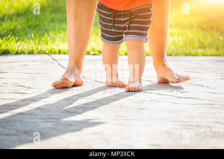 Mère et Bébé pieds prend des mesures à l'extérieur. Banque D'Images