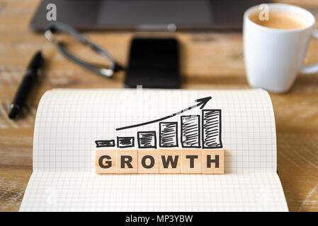 Gros plan sur ordinateur portable sur la table de bois, l'arrière-plan l'accent sur des pièces en bois avec des lettres de faire de la croissance et de l'augmentation de la flèche mot histogrammes. Banque D'Images