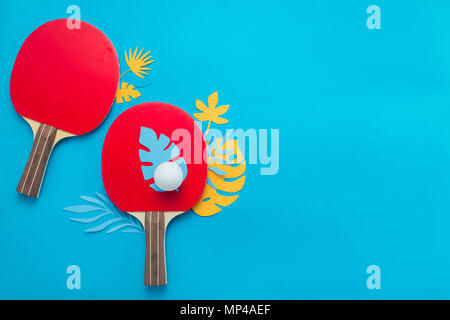 Ping pong jeu de plage, tongs, lunettes de soleil et les feuilles tropicales. Sports et loisirs télévision déposer sur un fond bleu lumineux avec copie espace. Banque D'Images