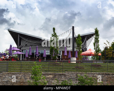 Les clients s'asseoir sous les parapluies, en face de nuages spectaculaires, à l'extérieur de la salle de dégustation à la New Belgium Brewing Company à Asheville, NC, USA Banque D'Images
