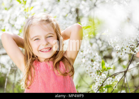 Happy little girl in cherry blossom garden Banque D'Images