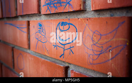 Dessins d'enfants sur le mur rouge par crayon bleu Banque D'Images