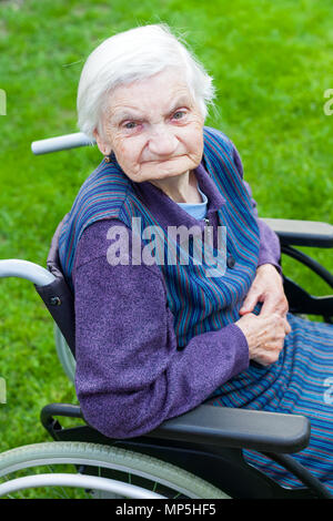 Vieille dame assise en fauteuil roulant souffrant de démence en plein air temps de dépenses Banque D'Images