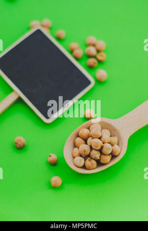 Pois chiches en cuillère en bois d'or sur fond vert et un tableau Banque D'Images