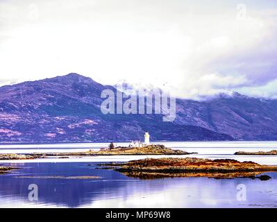 Phare sur Isle Ornsay navire de commerce.à rocky island, montagnes en arrière-plan. Île de Skye, Ecosse, Royaume-Uni. Banque D'Images