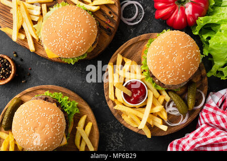 De savoureux hamburgers, cheeseburgers, frites, salade et plaid rouge textile cuisine table, vue d'en haut. Trois hamburgers et cheeseburgers, frites et ketc Banque D'Images