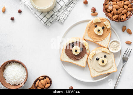Petit-déjeuner face animale toasts avec beurre de noix pour les enfants sur fond de béton avec copie espace pour le texte. L'art de l'alimentation, pour les enfants en bonne santé ou menu snack pour vegan Banque D'Images
