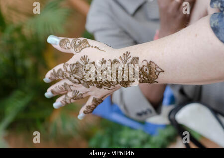 Un artiste à l'henné Shilparamam arts and crafts village, Hyderabad, Inde, l'application de pâte mehndi sur les mains d'une femme touriste. L'art et la diversité. Banque D'Images