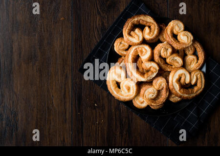 Palmier les Cookies dans la plaque noire sur la surface en bois. Concept de dessert. Banque D'Images