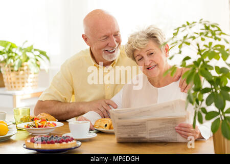 Happy senior woman reading a newspaper au petit-déjeuner avec son mari Banque D'Images