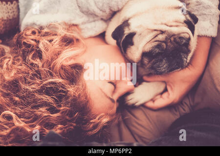 Caucasian woman dormir sous la couverture avec son chien pug blanc. L'amour et l'amitié à la maison Banque D'Images