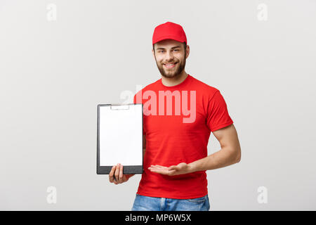 L'homme en uniforme rouge livraison holding white vide papier blanc isolé sur fond blanc. Copie espace publicité. Place pour le texte ou l'image Banque D'Images