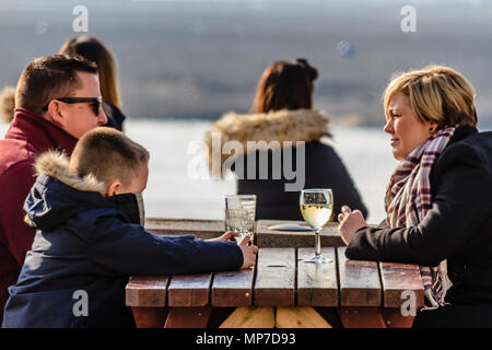 Famille de trois assis à une table de pub à l'extérieur avec des boissons, Devon, Feb 2018. Banque D'Images