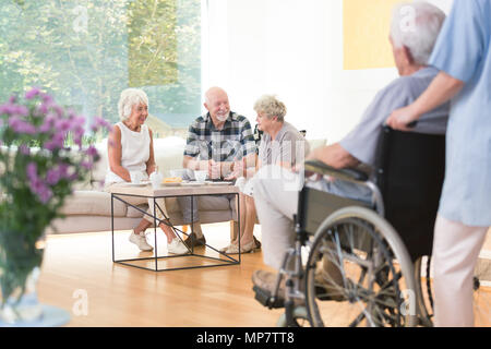 Groupe de personnes âgées des gens assis sur le canapé à l'heure du déjeuner dans la salle commune Banque D'Images