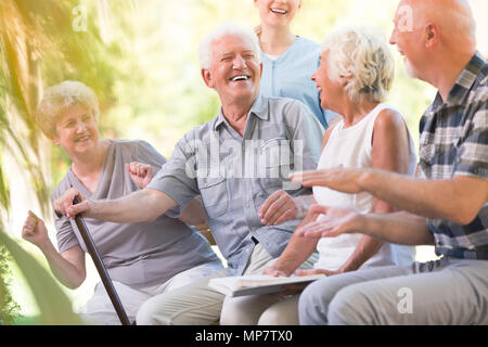 Group of smiling senior friends passer du temps ensemble assis dans le parc Banque D'Images