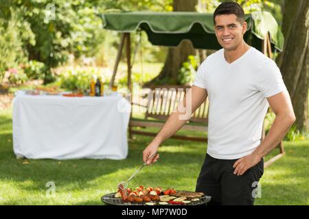 Young handsome man grilling dans le jardin Banque D'Images