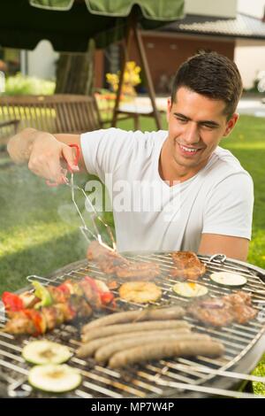 Jeune homme séduisant la préparation grill pour les amis Banque D'Images