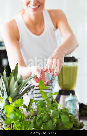 Femme en bonne santé dans la cuisine préparer le jus de légumes dans le mixer sur comptoir brillant avec des carottes Banque D'Images