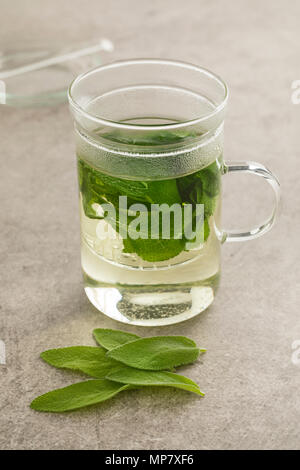 Verre de thé de sauge en bonne santé avec des feuilles décorées Banque D'Images