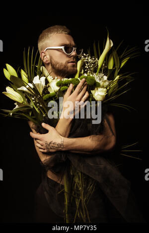 Avec l'homme élégant bouquet de fleurs blanches sur fond noir Banque D'Images