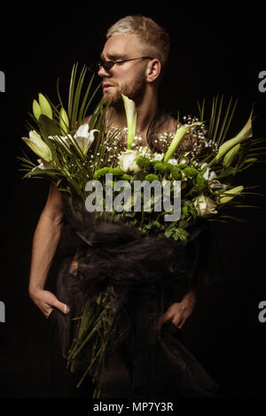 Avec l'homme élégant bouquet de fleurs blanches sur fond noir Banque D'Images