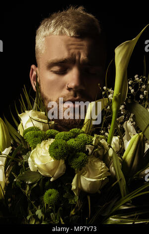 Avec l'homme élégant bouquet de fleurs blanches sur fond noir Banque D'Images