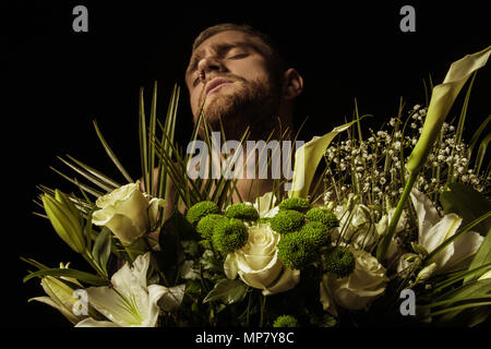 Avec l'homme élégant bouquet de fleurs blanches sur fond noir Banque D'Images