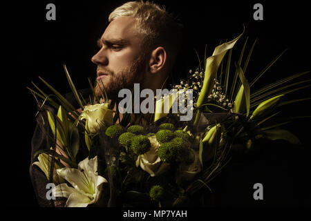 Avec l'homme élégant bouquet de fleurs blanches sur fond noir Banque D'Images