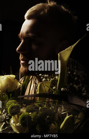 Avec l'homme élégant bouquet de fleurs blanches sur fond noir Banque D'Images