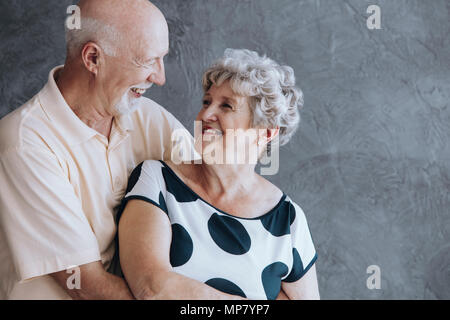 Professionnels personnes âgées couples célébrant leur anniversaire de mariage contre mur en béton Banque D'Images