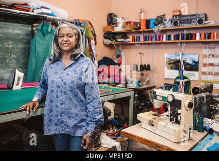 Couturière à maturité par une table debout dans son atelier de couture Banque D'Images