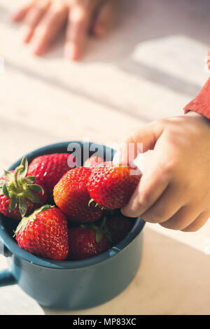 La main de l'enfant prend les fraises Banque D'Images