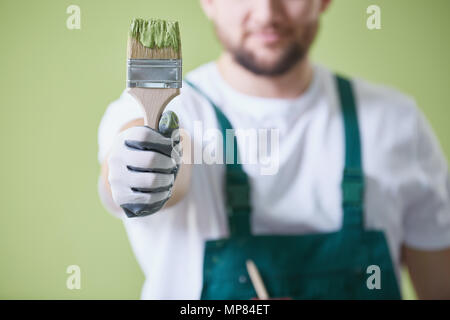 Travailleur en tenant le pinceau uniforme avec la peinture verte Banque D'Images