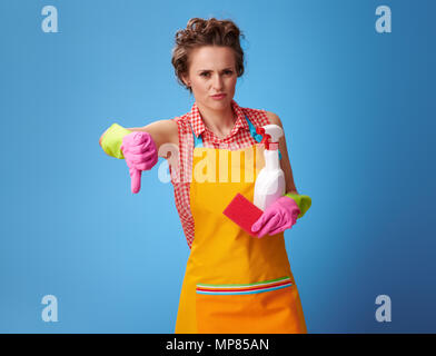 Grand temps de nettoyage. moderne avec des gants en caoutchouc et d'une éponge de cuisine et une bouteille de détergent showing Thumbs down isolé sur blue Banque D'Images