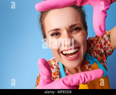 Grand temps de nettoyage. smiling ménagère moderne dans un tablier jaune avec mains ossature bois isolé sur blue Banque D'Images