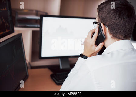 Au cours de l'épaule de courtier en bourse et trading en ligne tout en acceptant les commandes par téléphone. Plusieurs écrans d'ordinateur ful de graphiques et analyses de données en arrière-plan Banque D'Images