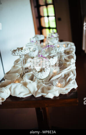 Table avec des pots de verre contenant des bonbons aux amandes italiennes traditionnelles, des bonbons pour les mariages Banque D'Images