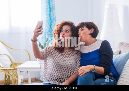 Deux jeunes femmes à prendre des photos avec un téléphone mobile à la maison faire nice et des expressions drôles. meilleurs amis que l'amour pour communiquer sur le net avec frie Banque D'Images