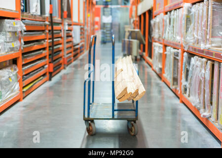 Panier de construction dans le bâtiment Magasin. Chargé avec des charrettes conseils. magasin de matériaux de construction. Les armoires avec planches, bois et matériaux de construction. Banque D'Images