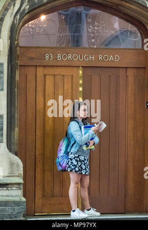 Une jeune femme debout dans l'embrasure d'une vérification d'un téléphone mobile ou smartphone à la mode dans la ville de Londres. jeune femme à l'aide d'un smartphone. Banque D'Images