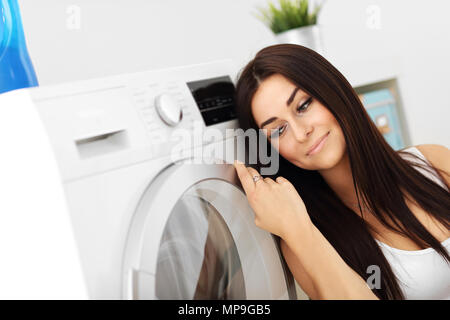 Photo de jeune femme au foyer avec une laverie à côté de lave-linge Banque D'Images