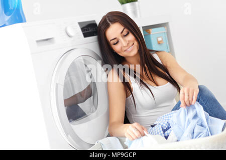 Photo de jeune femme au foyer avec une laverie à côté de lave-linge Banque D'Images