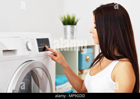 Photo de jeune femme au foyer avec une laverie à côté de lave-linge Banque D'Images